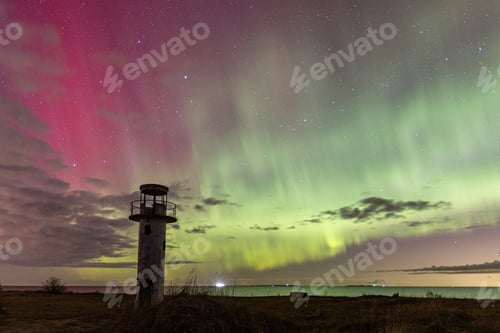 Preview: Lighthouse situated on the beach with a beautiful, colorful aurora sky in the background