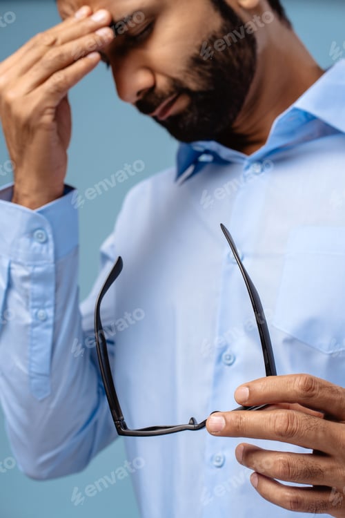 Preview: Portrait of unhappy sad middle aged, Indian man having headache holding eyeglasses, with closed eyes