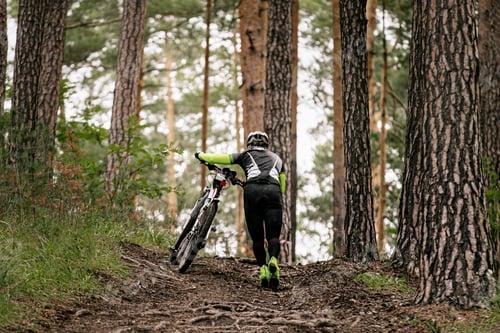 Preview: man cyclist with mountain bike goes uphill