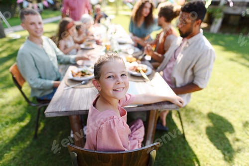 Visualização: Retrato de menina sentada à mesa com a família e amigos na festa do jardim da família.
Família