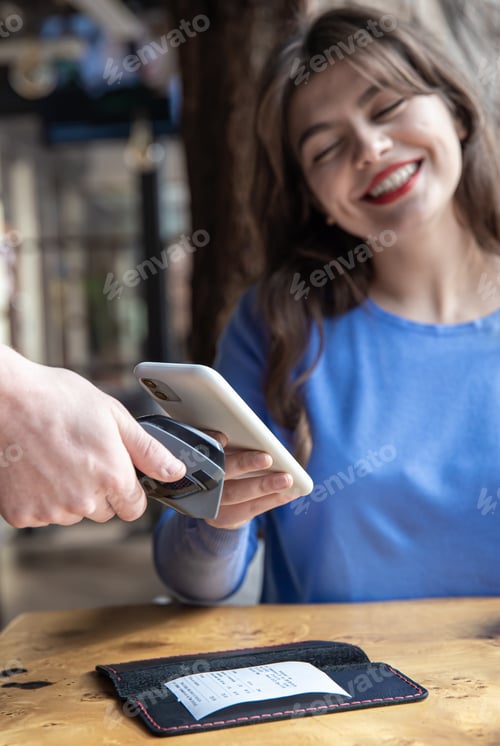 Preview: Paypass, male hands holding black pos terminal and female brings smartphone.