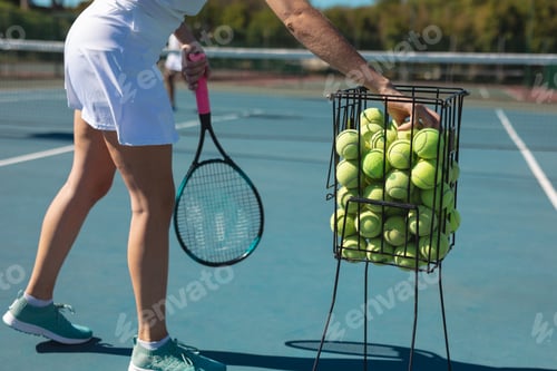 Preview: Low section of young female caucasian player practicing tennis at court on sunny day