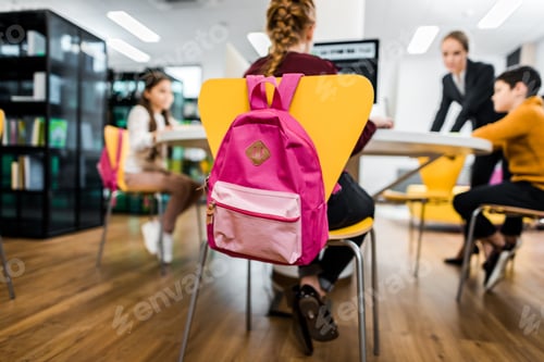 Preview: young teacher and schoolchildren studying with desktop computers in library