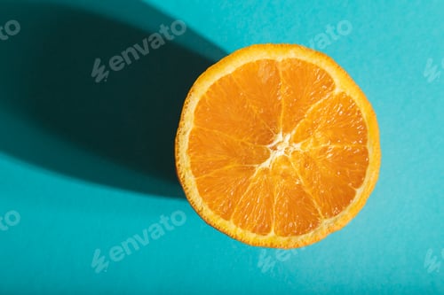 Preview: Ripe cut orange on blue pastel background. Top view, close up, hard light.