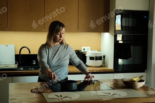 Preview: Woman stirs food in pan in kitchen