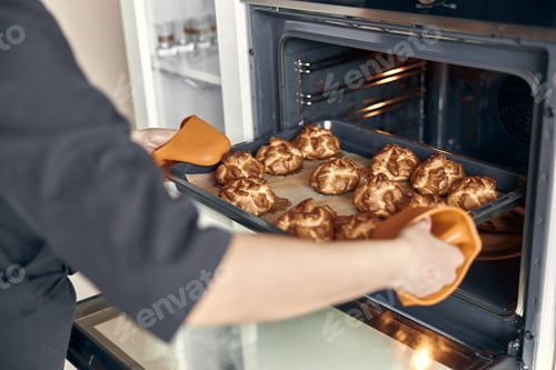 Preview: Professional confident woman is preparing custard cakes at light modern kitchen at home