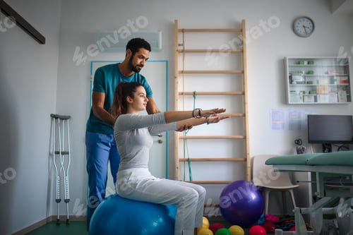 Preview: Young male physiotherapist exercising with young woman patient in a physic room