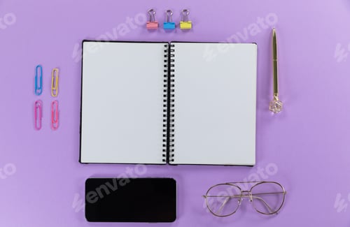 Preview: View of a black smartphone, a notebook, a pen, glasses and paperclips on plain purple background