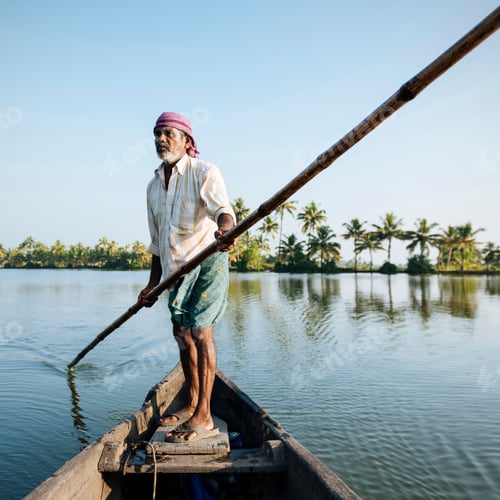 Preview: Fisherman standing in a boat, navigating through calm waters at sunrise.