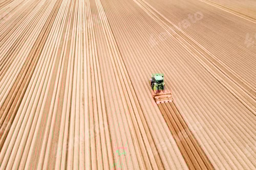 Preview: Lonely tractor on agricultural field with rows of plowed soil