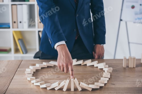 Preview: partial view of risk manager stopping domino effect of falling wooden blocks