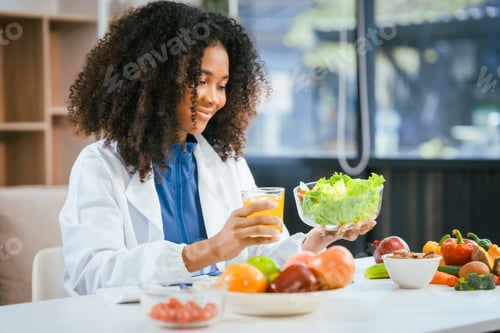 Preview: An African American female nutritionist sits at table,consulting online with patients.talks about