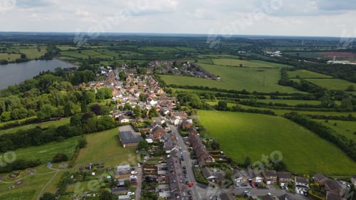 Preview: Aerial view of a village with green fields and a lake.