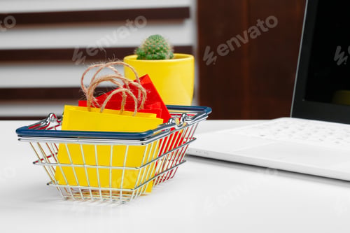 Preview: Online shopping concept. Shopping cart, laptop on the desk