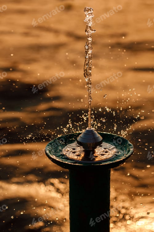 Preview: Drinking fountain with flowing water on the beach near lake on sunset