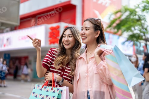 Preview: Asian young women shopping goods outdoor in shopping street at night.