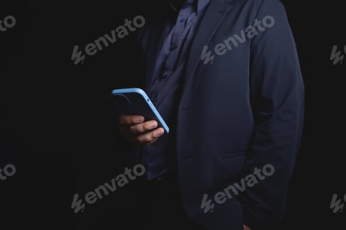 Preview: man in suit holding smartphone in dark setting