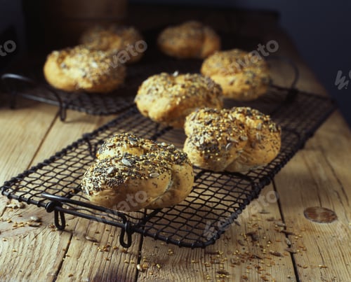 Preview: Knotted seeded bread rolls on wooden table, fresh from oven