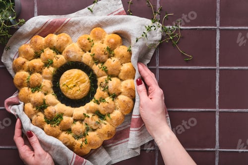 Preview: Female hands holding roasted camembert cheese and homemade bread heart shaped and thyme on rustic ba