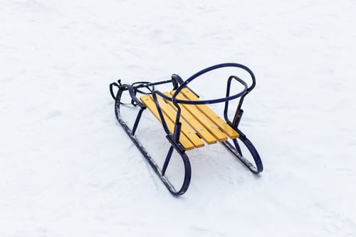 Preview: Wooden sleigh with blue metal frame and yellow seat on snowy surface showing children's winter games