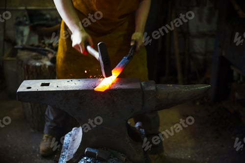 Preview: A blacksmith strikes a length of red hot metal on an anvil with a hammer in a workshop.