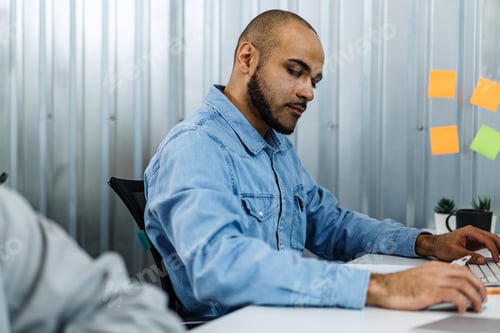 Preview: Portrait of young man sitting and working at his desk in the office