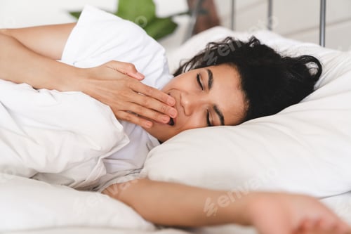 Preview: Tired sleepy young african woman yawning in her bed before sleeping.