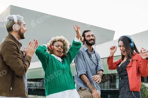 Preview: Young diverse friends dancing and listen music with headphones outdoor in the city