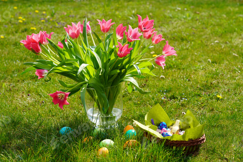 Preview: Pink roses in a vase, colorful Easter eggs, and a basket with chocolates on the grass