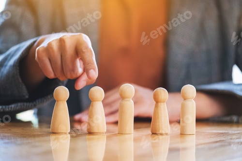 Preview: Businesswoman choosing and pointing finger at wooden people from a group of employees
