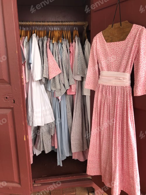 Preview: Pretty colonial pastel color long gown dresses hanged in a closet.