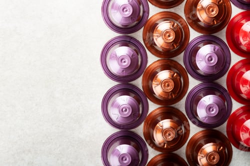 Preview: Espresso coffee capsules or pods and coffee beans on grey background