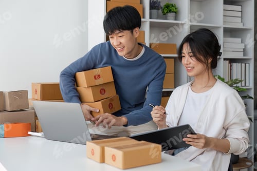Preview: Happy couple people packing parcel boxes, couple lover checking order online on laptop at home