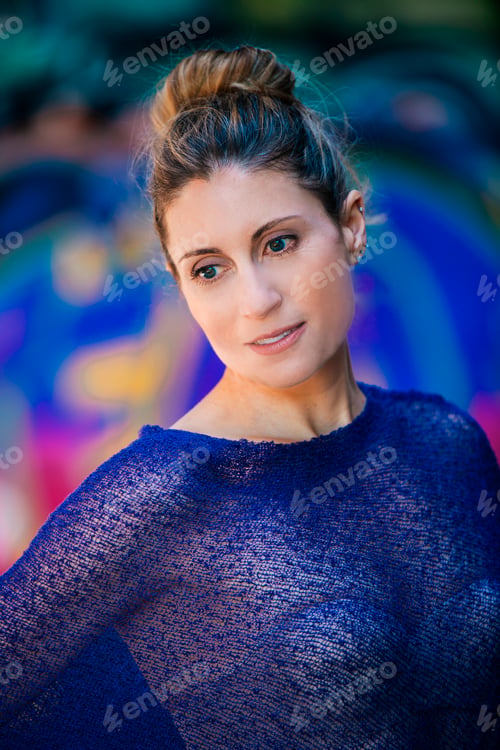 Preview: Woman in a blue mesh top poses with a soft gaze against a brightly colored background