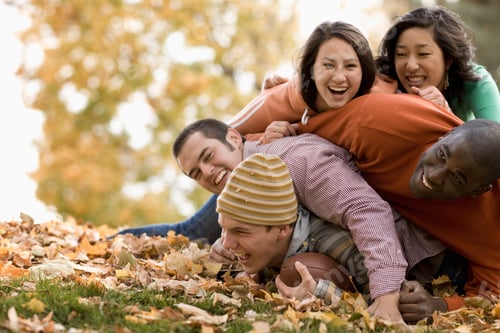 Preview: A group of people, adults and young people, playing a game of football among the autumn leaves.