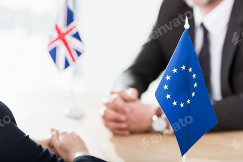 Preview: selective focus of european union flag near ambassadors with clenched hands