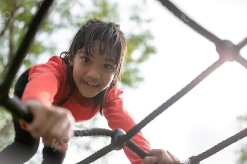 Preview: Cute little girl toddler having fun on the playground, climbing and sliding down