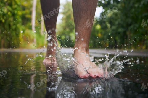 Preview: Barefoot leg of man stepping to puddle
