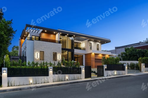 Preview: Modern two-story house with illuminated exterior at twilight.
