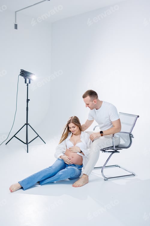 Preview: A pregnant woman and a man are standing on a white background. Beautiful young attractive pregnant