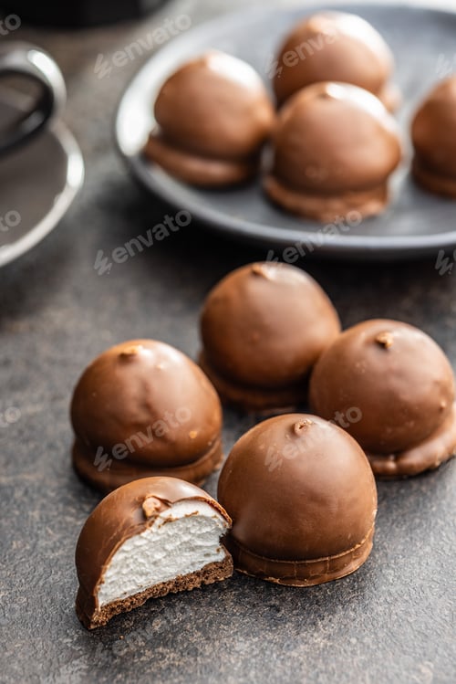 Preview: Chocolate covered marshmallows. Sweet dessert on black table.