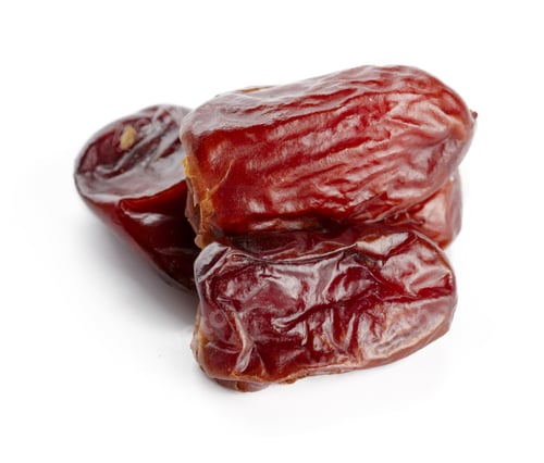 Preview: Fresh dates piled together on a plain white surface in bright lighting