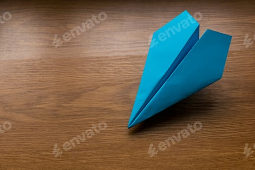 Preview: Blue paper plane on wooden background with copy space.