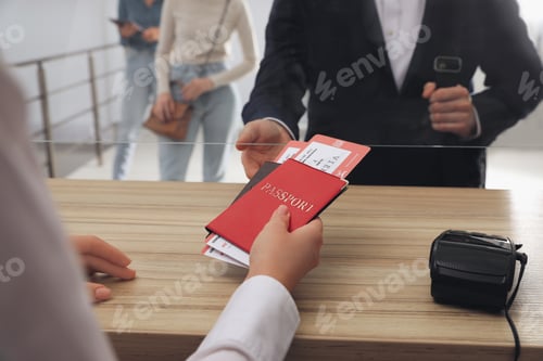 Preview: Agent giving passports with tickets to client at check-in desk in airport, closeup