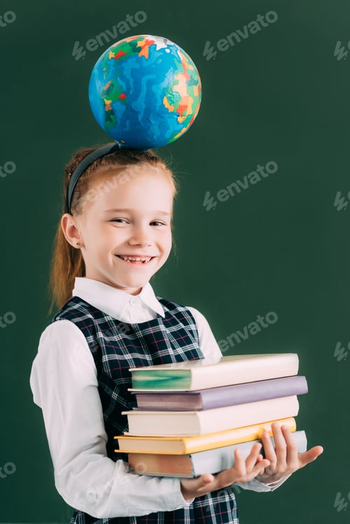 Preview: adorable little schoolchild with globe on head holding pile of books and smiling at camera