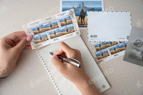 Preview: TERNOPIL, UKRAINE - June 28: Postage stamps "Russian warship... done". Woman writing letter