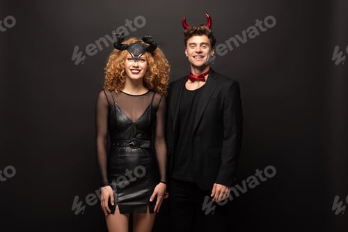 Preview: beautiful smiling couple posing in halloween costumes on black