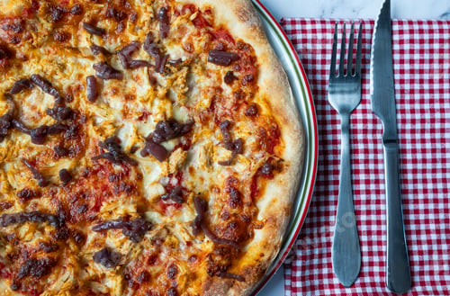 Preview: Background for restaurants. Top view of a chicken pizza with knife and fork.