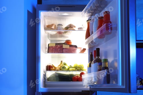 Preview: Open refrigerator full of products in kitchen at night