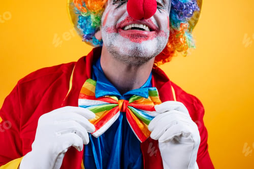 Preview: Happy clown adjusts rainbow bow tie, vibrant yellow background.